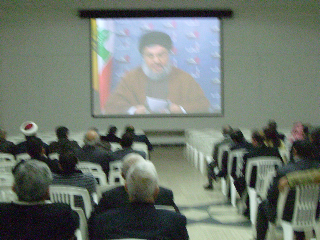 The leader of Hezbollah, Hassan Nasralla, for security reasons talking on video, here in a room adjacent to the packed lecture hall.