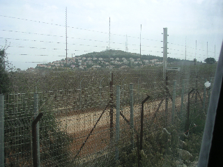 The border with Palestine showing an Israeli kibbutz on the hill.